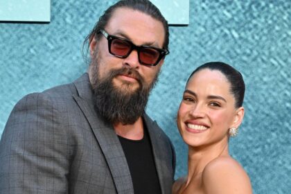 Adria Arjona and Jason Momoa share a sweet kiss on the ‘Onslaught’ red carpet