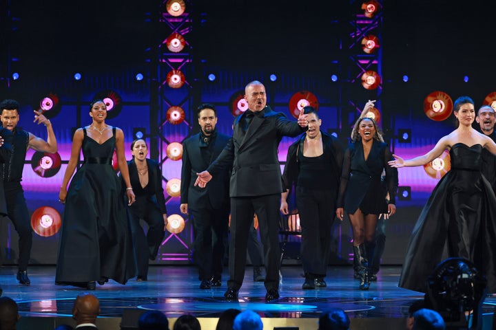 The cast notably eschewed the colonial garb of the stage production for all-black suits and gowns.