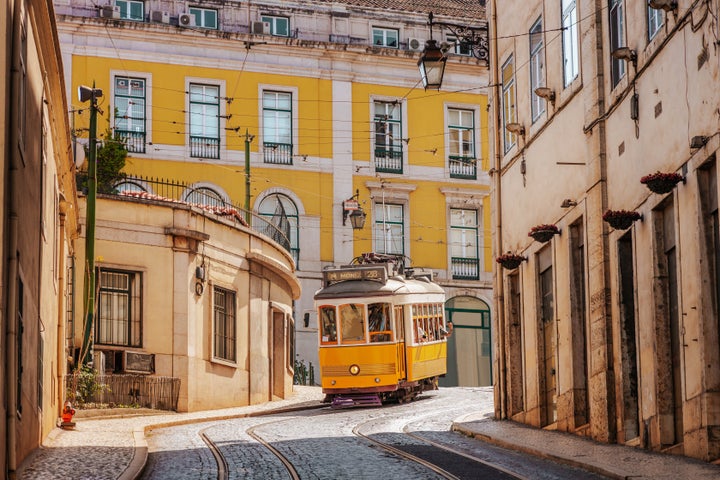 A cobblestone street in Lisbon, Portugal, with beautiful yellow architecture and evening light.