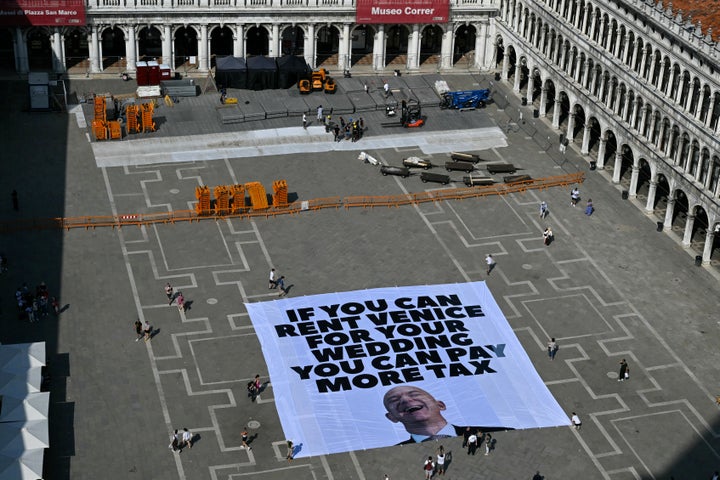 Activists of international environmental group Greenpeace deploy a giant banner displaying a picture of Jeff Bezos and reading "If you can rent Venice for your wedding you can pay more tax" at St Mark square in Venice on June 23, 2025. Venice will host the wedding of Amazon Founder and CEO Jeff Bezos and journalist Lauren Sanchez before the end of the month with more than 200 guests expected to attend. (Photo by Stefano Rellandini / AFP) (Photo by STEFANO RELLANDINI/AFP via Getty Images)